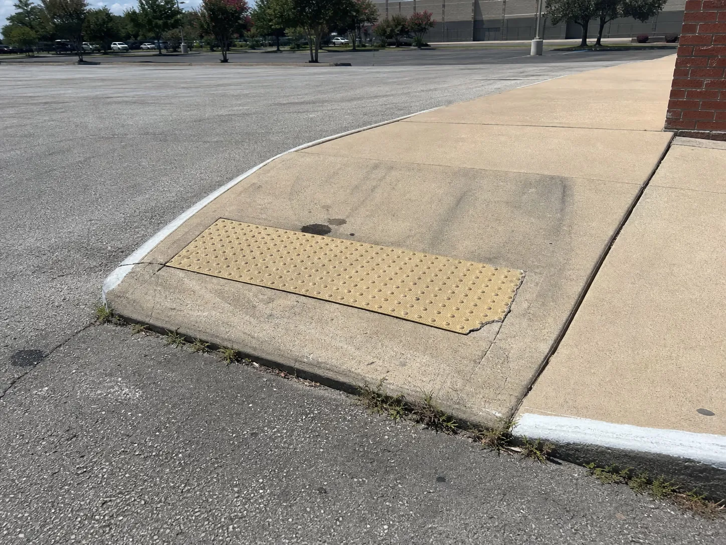Concrete curb ramp with a detectable warning panel at a commercial parking lot