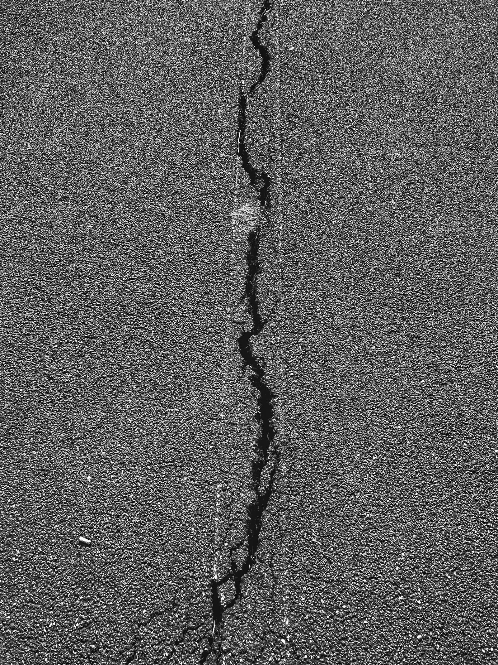 Close-up of a linear crack in an asphalt surface