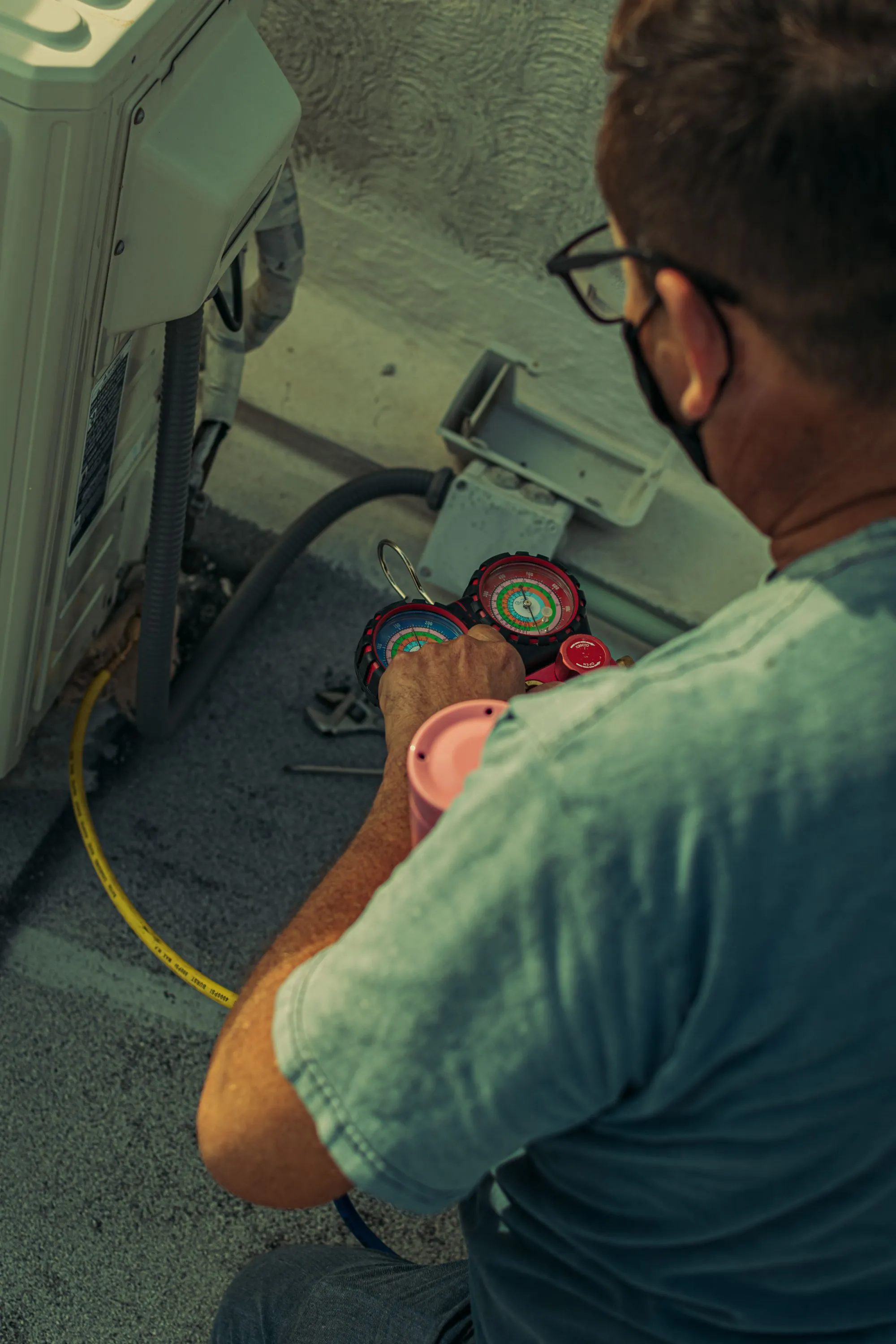 HVAC technician checking refrigerant gauges on a commercial rooftop unit during preventive maintenance
